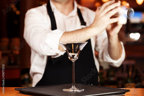 Barman in making cocktail at a nightclub. Nightlife concept. No face. Shaking drink