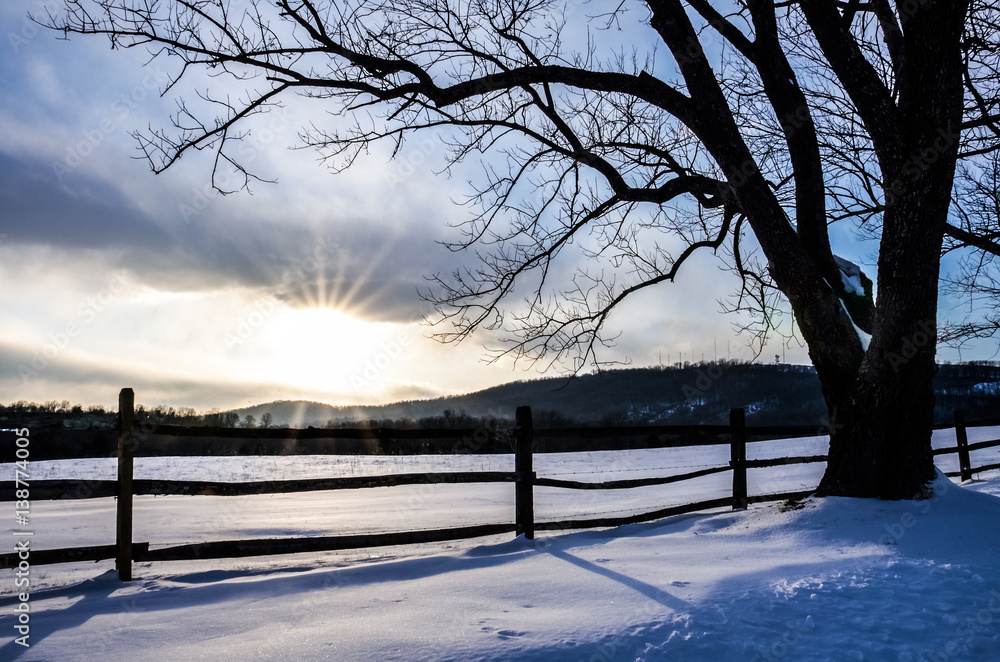 Fototapeta premium Countryside field in Virginia covered in snow during winter with sunset