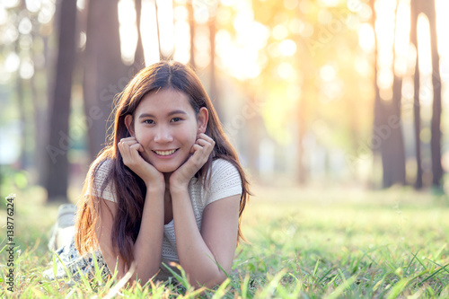 Happy young asian woman laying down on grass in the park in vintage color tone