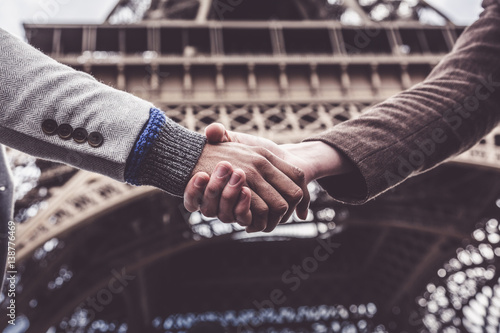 Two Men Shaking Hands By The Eiffel Tower In Paris