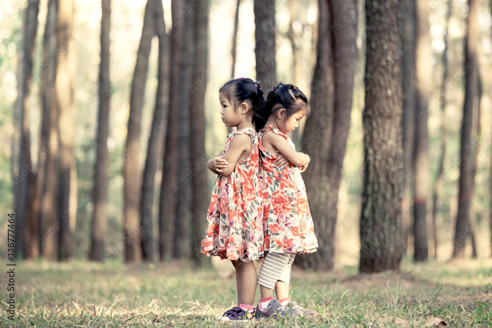 two asian little girls hug their chest and turn back to each other and feel  sad in vintage color tone Stock Photo | Adobe Stock