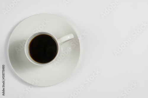 Top view of a white cup of coffee on white saucer