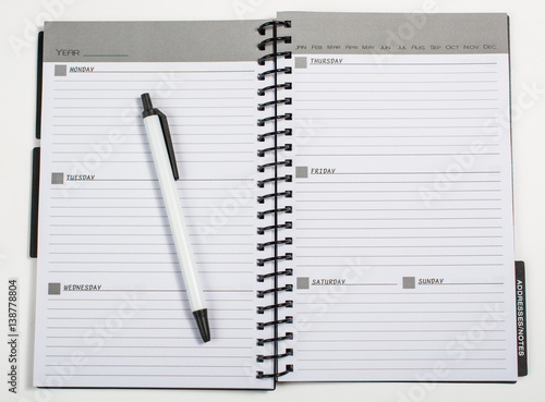 Weekly planner opened with a pen laying on it