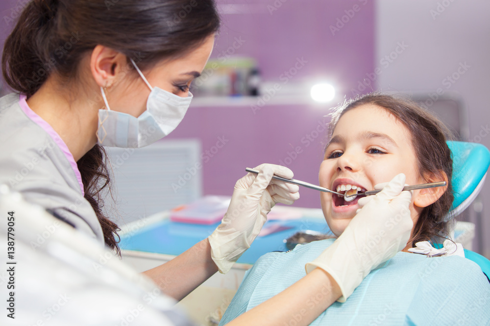 Close-up of pretty little girl opening his mouth wide during treating her teeth by the dentist Close-up of pretty little girl opening his mouth wide during treating her teeth by the dentist