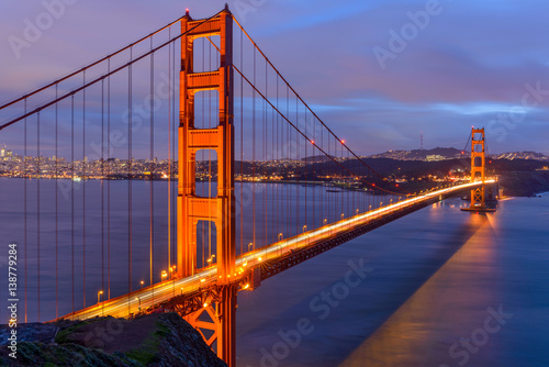 Fototapeta Naklejka Na Ścianę i Meble -  Sunset Golden Gate Bridge - A cloudy-winter-day sunset view of Golden Gate Bridge, looking from Hilltop at Marin Headlands toward San Francisco Peninsula at south. San Francisco, California, USA. 