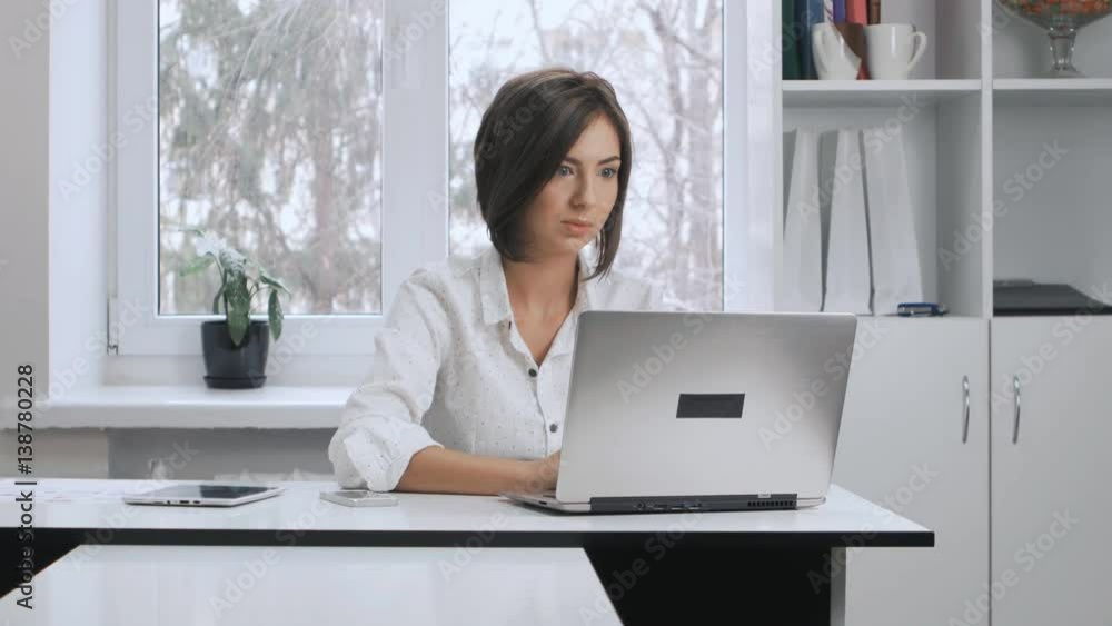 attractive business woman in a white shirt works at a laptop in the office attractive business woman in a white shirt works at a laptop in the office