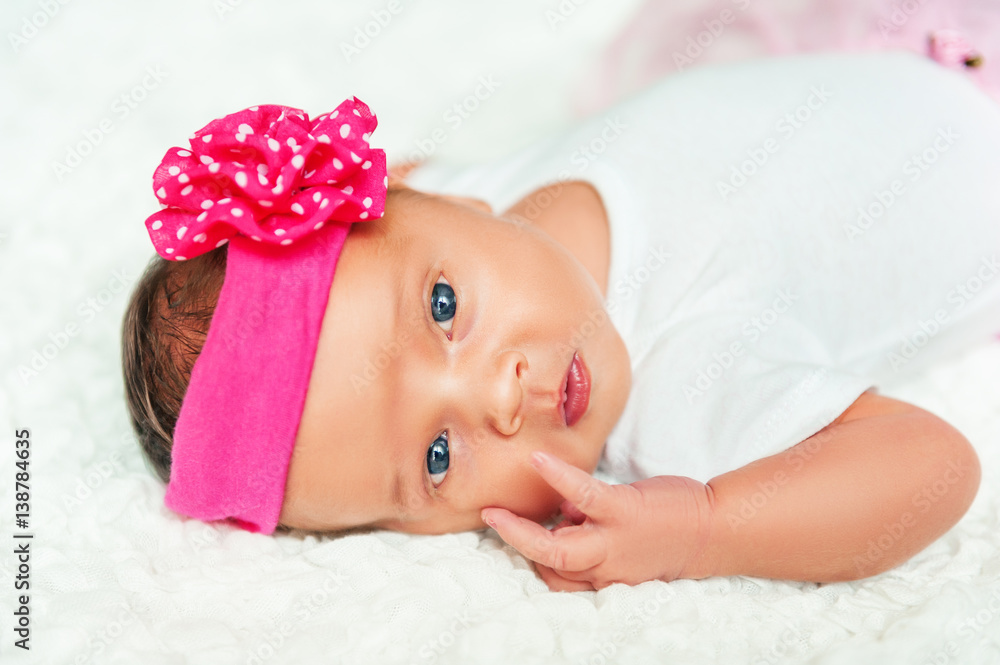 Close up portrait of adorable 1 week old baby girl wearing bright pink headband Close up portrait of adorable 1 week old baby girl wearing bright pink headband