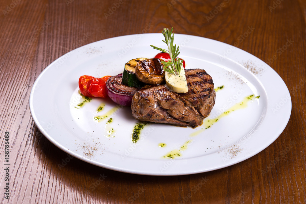 thick steak with rosemary and fried vegetables cheese on white plate