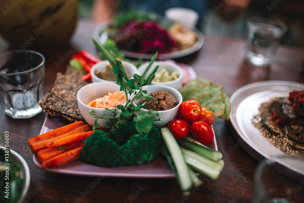 The plate full of vegetables, sauces and bread on the wooden table The plate full of vegetables, sauces and bread on the wooden table