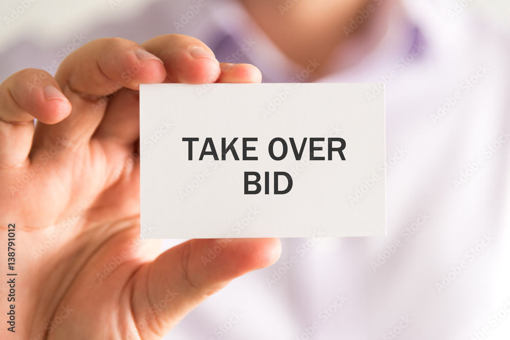Businessman holding a card with TAKE OVER BID message Businessman holding a card with TAKE OVER BID message