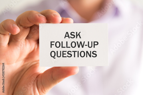 Businessman holding a card with ASK FOLLOW-UP QUESTIONS message