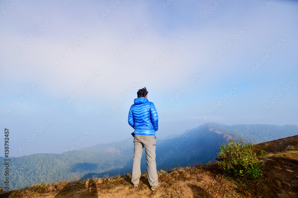 man stand on top mountain looking view at morning. subject is soft focus and low key