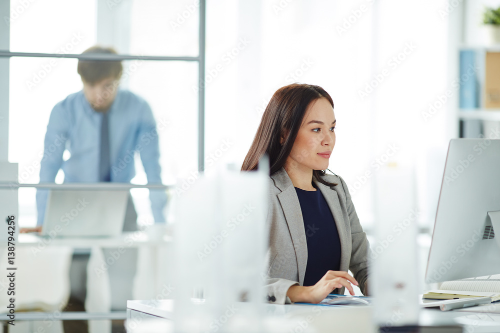 Portrait of confident young businesswoman busy working at desk in modern office, looking at computer screen and typing Portrait of confident young businesswoman busy working at desk in modern office, looking at computer screen and typing