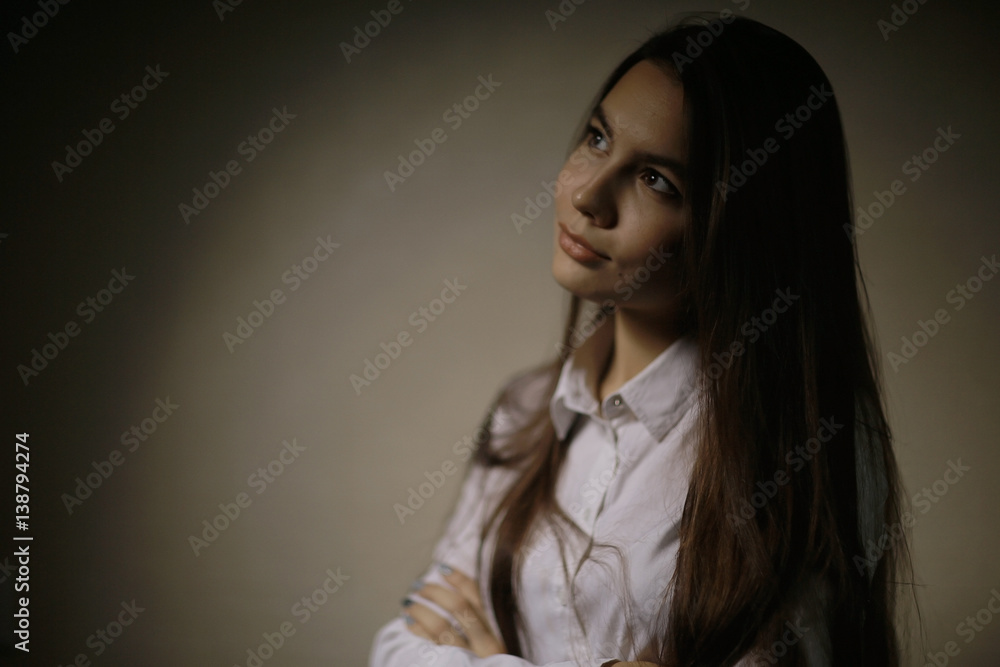Portrait of a young adult woman in a white shirt thoughtful