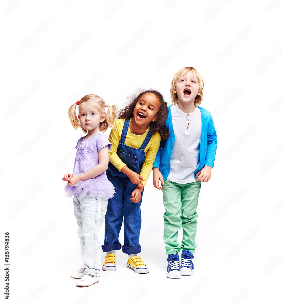 Studio portrait of children against white background: full body shot of three kids in colorful clothes, African girl, blond boy and cute little girl, laughing and screaming loudly with mouths open Studio portrait of children against white background: full body shot of three kids in colorful clothes, African girl, blond boy and cute little girl, laughing and screaming loudly with mouths open