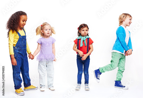 Studio portrait of children against white background: cutout of four kids in bright clothes, two girls holding hands, boy running and confused little girl