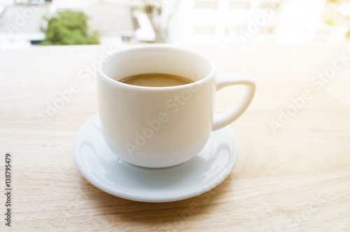 white cup of coffee on wooden table and copy space, soft focus