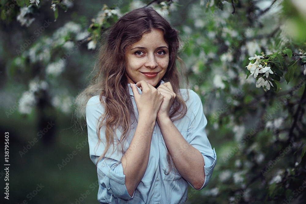 young adult girl enjoys smell of spring flowers apple
