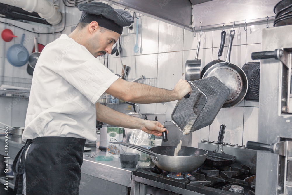 chef transferring pasta pan, commercial kitchen