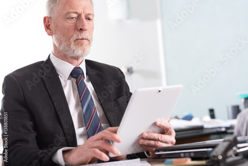 Portrait of senior businessman working on tablet