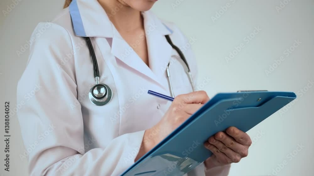 Female doctor filling medical form in clinic. Female doctor filling medical form in clinic.