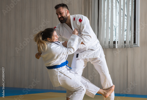 Woman and man judo fighters in sport hall
