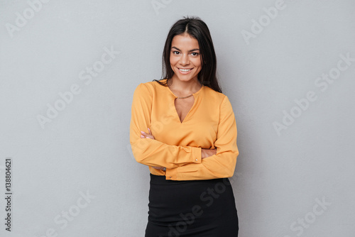 Woman standing with hands folded and looking at camera photo