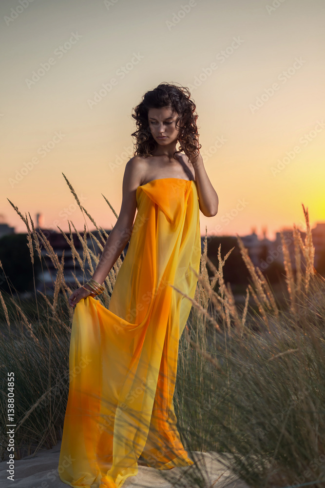 Obraz premium Portrait of a beautiful woman on the beach at sunset