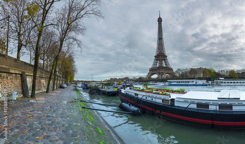 Panoramic view of the Eiffel Tower and Jena bridge from the river Seine embankment. Dramatic cloudscape. Paris, France.