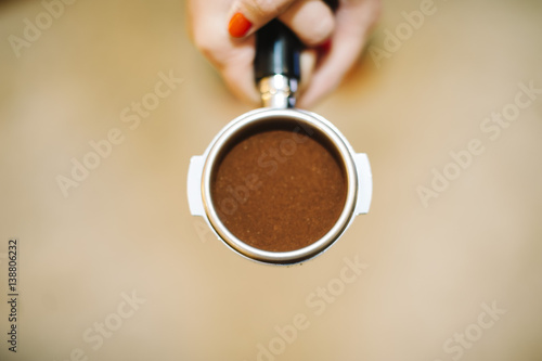 Barista woman holding portafilter with a tamper on it photo