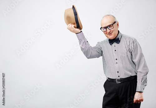 Photography Portrait of elegant retired man in formalwear and bow tie taking his bowler hat