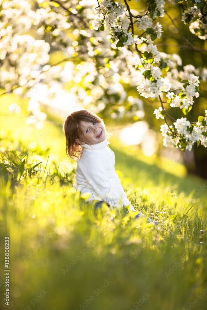 child in white sweater and jeans, spring flowers child in white sweater and jeans, spring flowers