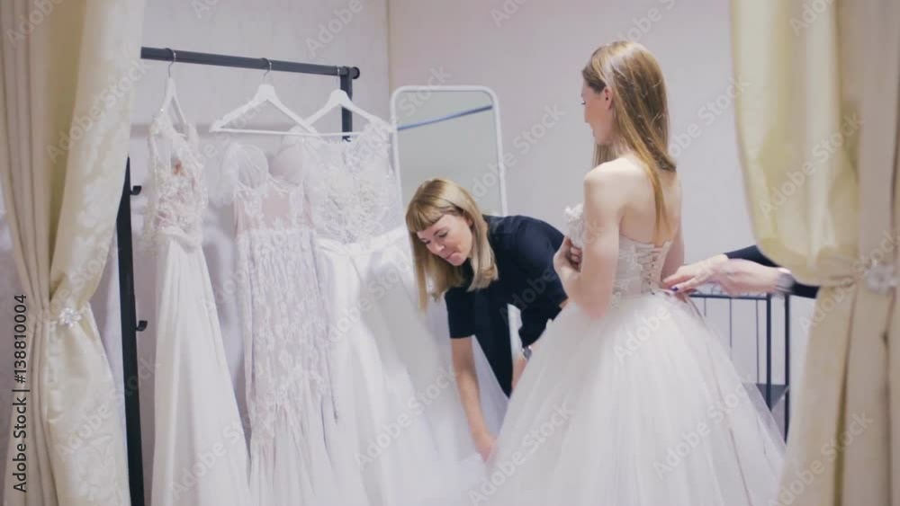 Young woman chooses a wedding dress in bridal shop Young woman chooses a wedding dress in bridal shop