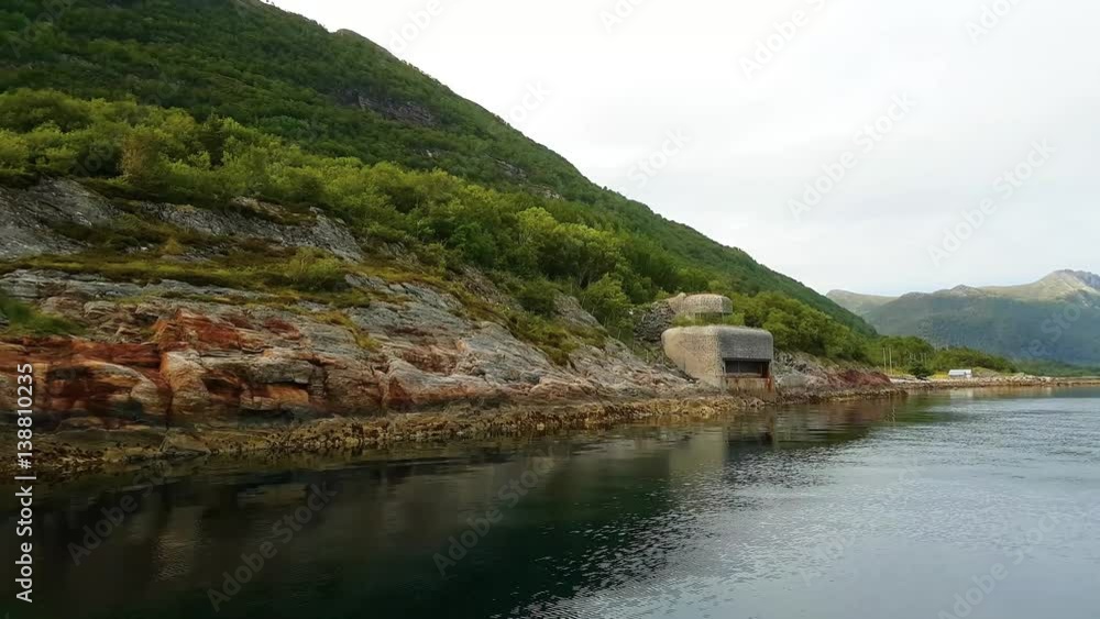 Yacht sailing along green hilly coast with pillbox of second world war in calm waters somewhere in Norway. Yacht sailing along green hilly coast with pillbox of second world war in calm waters somewhere in Norway.