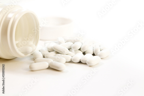 Pills spilling out of pill bottle on white