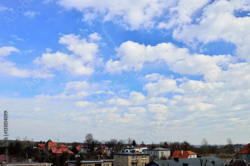 Chmury na niebieskim niebie nad dachami domów.