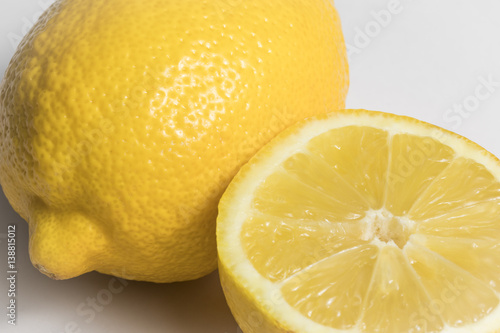 Close up of a whole lemon and half lemon on a white background