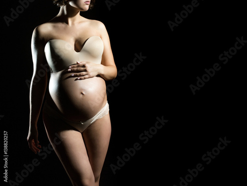 pretty pregnant woman with round belly isolated on black © Volodymyr