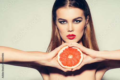 Pretty girl with red lips and orange grapefruit
