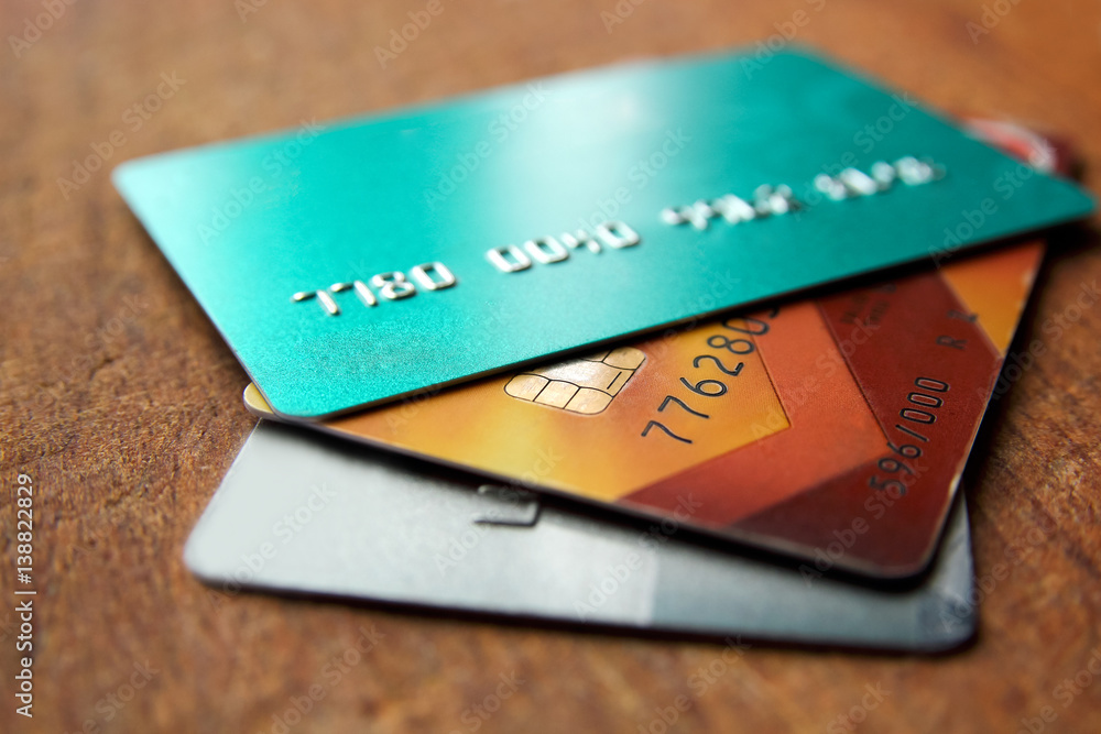 Stack of credit cards on a wooden background with selective focus, close up view. Stack of credit cards on a wooden background with selective focus, close up view.