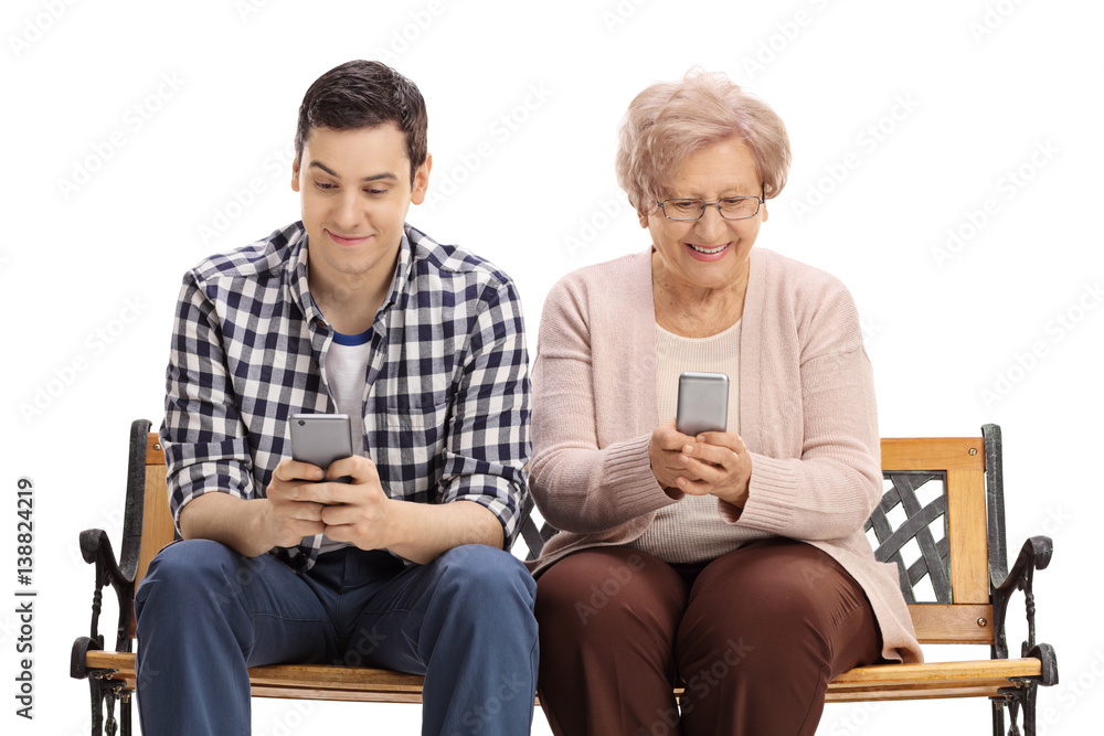 Young man and elderly woman on bench looking at phones