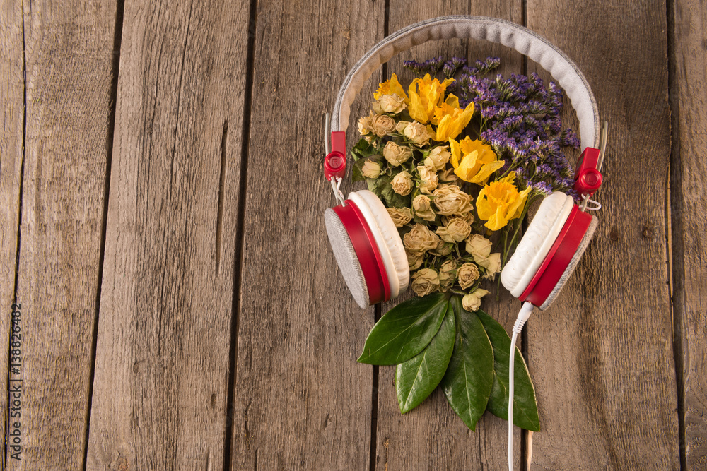 Top view of Spring floral composition with headphones and variety of flowers and leaves on wooden table