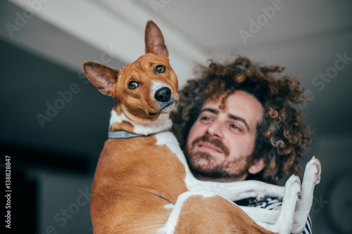 Crazy hair hipster staring lovingly at purebred dog while hugging him