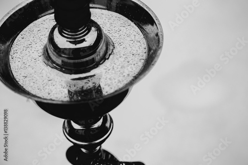 Big hookah for tobacco made of metal, glass and ceramics. Snowing. Snow background. White