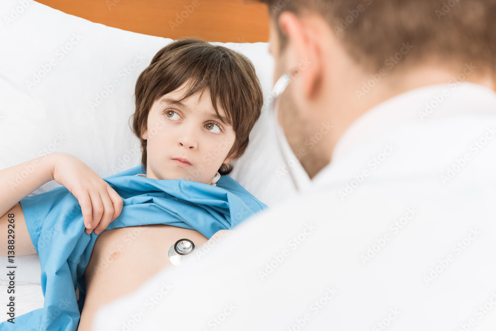 doctor examining pensive little boy with stethoscope Stock Photo