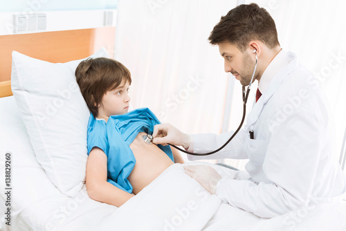 side view of doctor examining little boy with stethoscope