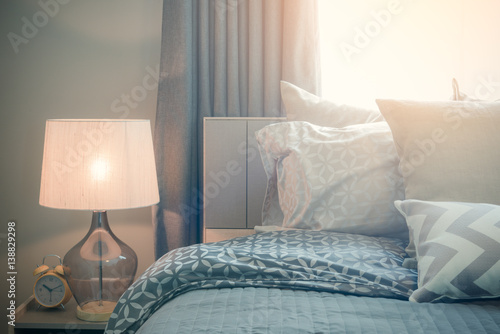 classic lamp style with alarm clock on table side in cozy bedroom