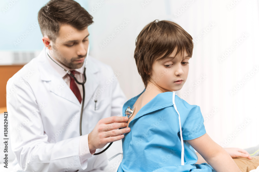 doctor in medical uniform examining little boy with stethoscope doctor in medical uniform examining little boy with stethoscope