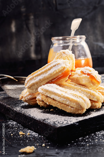 Shortbread butter cookies with apricot jam on black wooden background with free text space. Selective focus.