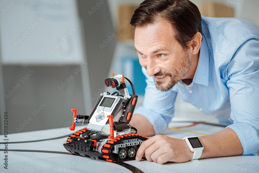 Cheerful engineer testing the robot Cheerful engineer testing the robot